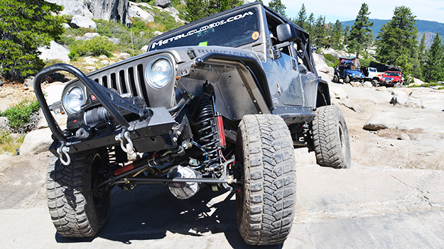 silver jeep wrangler with red 6-Pak suspension and black coils and black metalcloak fenders on offroad granite rock Rubicon trail with other Jeeps in background