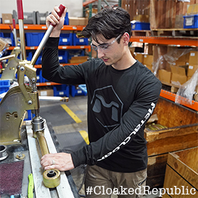 A Man Working With A Black Long Sleeve Shirt That Has The MetalCloak Hex Icon on the Front of His Shirt