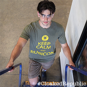 A Man Walking Up Stairs With A Military Green Shirt That Reads Keep Calm and Rubicon