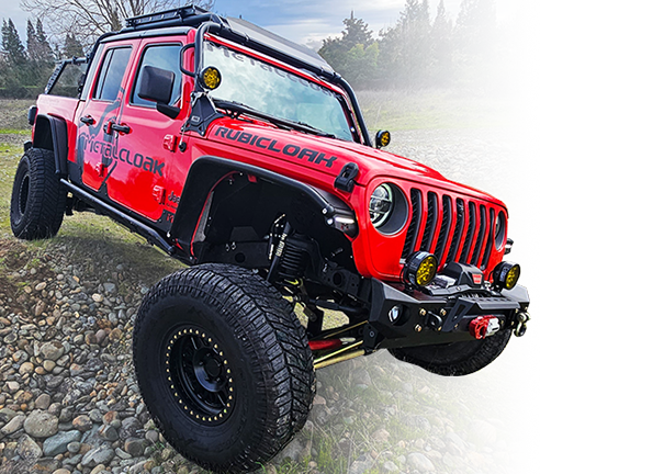 Red MetalCloak Jeep JT Truck with black Vinyl MetalCloak decals and black powdercoated fenders driving over gravel and grass trail